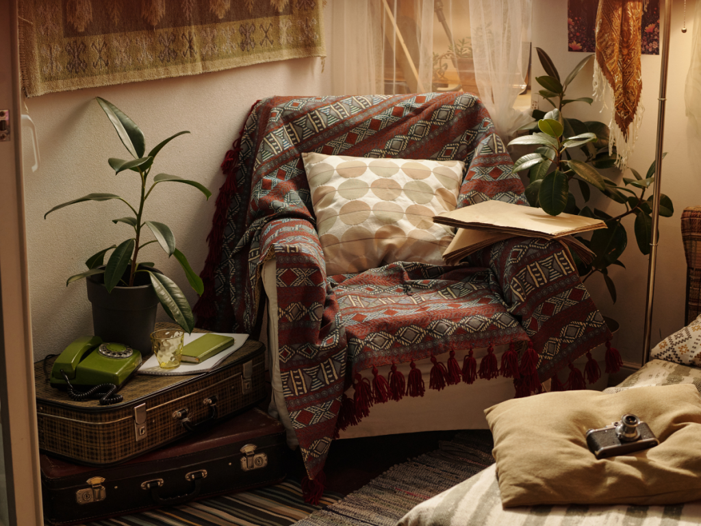 Charming vintage style reading nook with comfy armchair and blanket surrounded by green plants and vintage suitcases