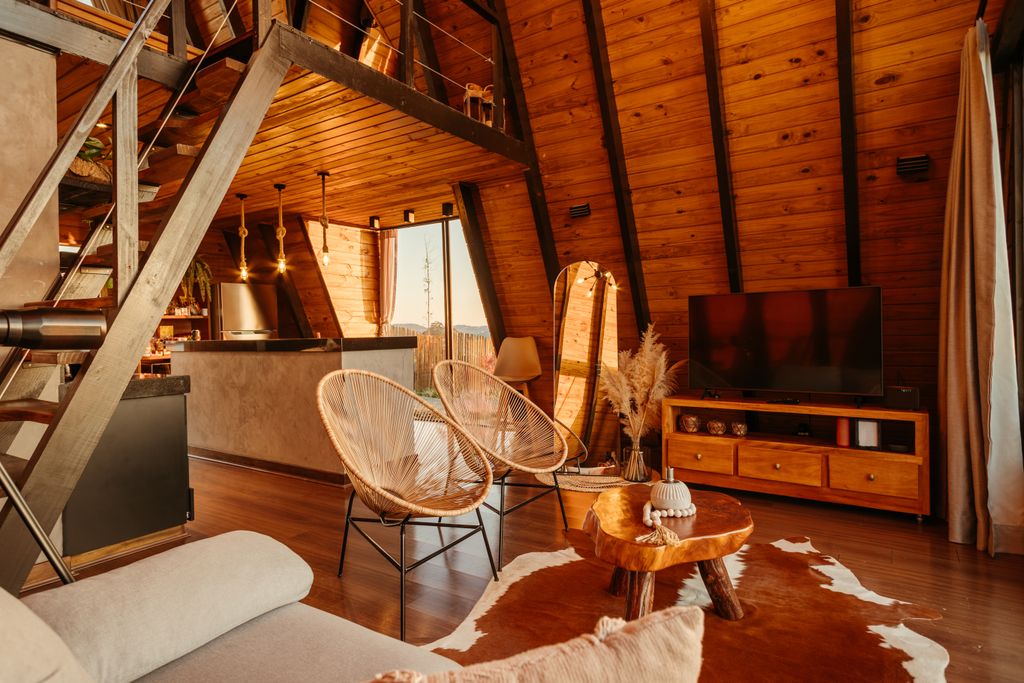 Cosy mountain lodge open plan living room with amber lighting and cowhide rug along with rustic wooden decor.