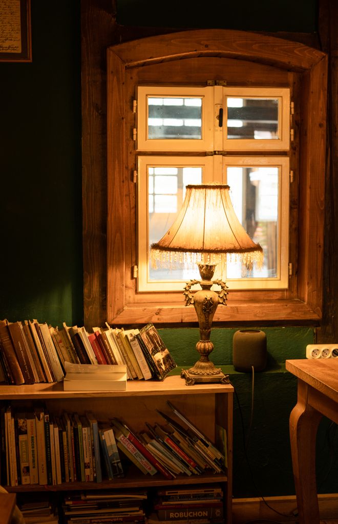 Intricate living room lamp with scalloped fabric lampshade, tassels and a warm glow in  cabin.