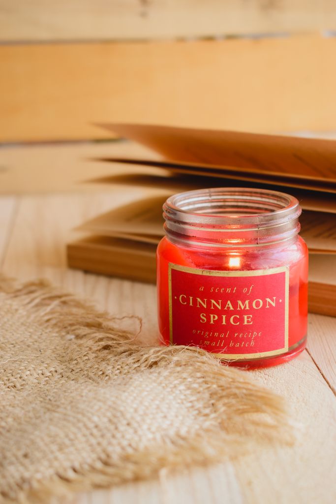 Warm cosy autumn ambiance with a cinnamon-scented candle and book pages.
