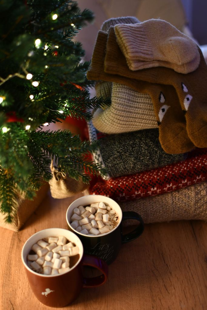 Warm up with stacked knits and hot cocoa under a Christmas tree.