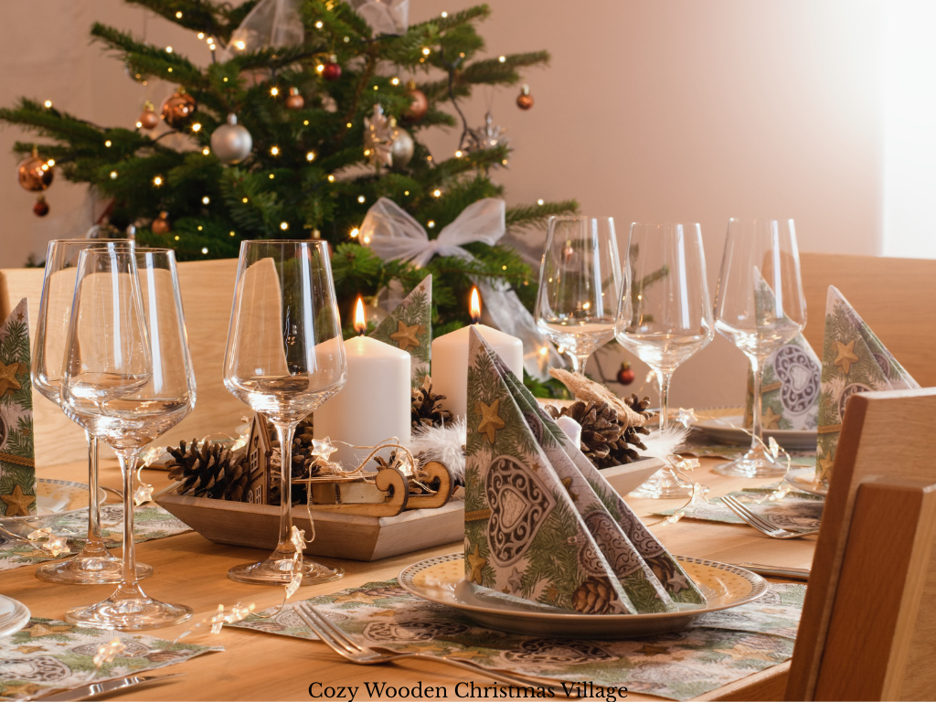 Wooden tray centerpiece with white pillar candles, a wooden sleigh, tiny house, star ornament, acorns and fairy lights on a plain wood table