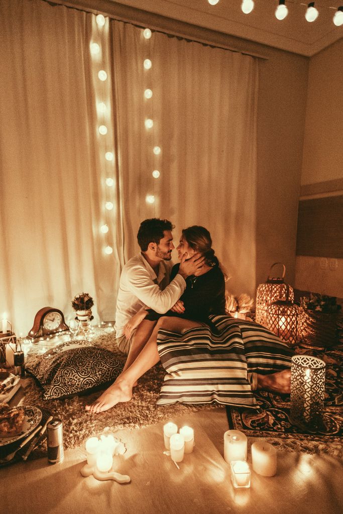 Couple embracing in a romantic candlelit room adorned with string lights for a autumn date night ideas at home