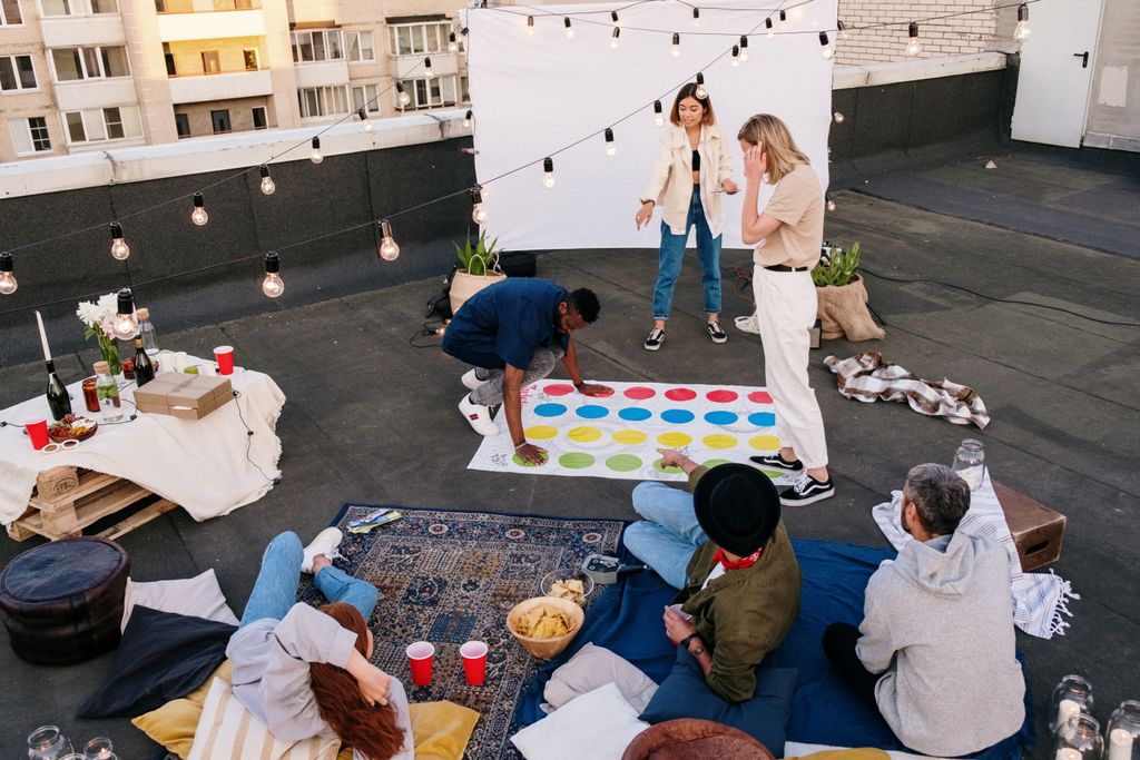 Group of friends at garden party playing twister board game