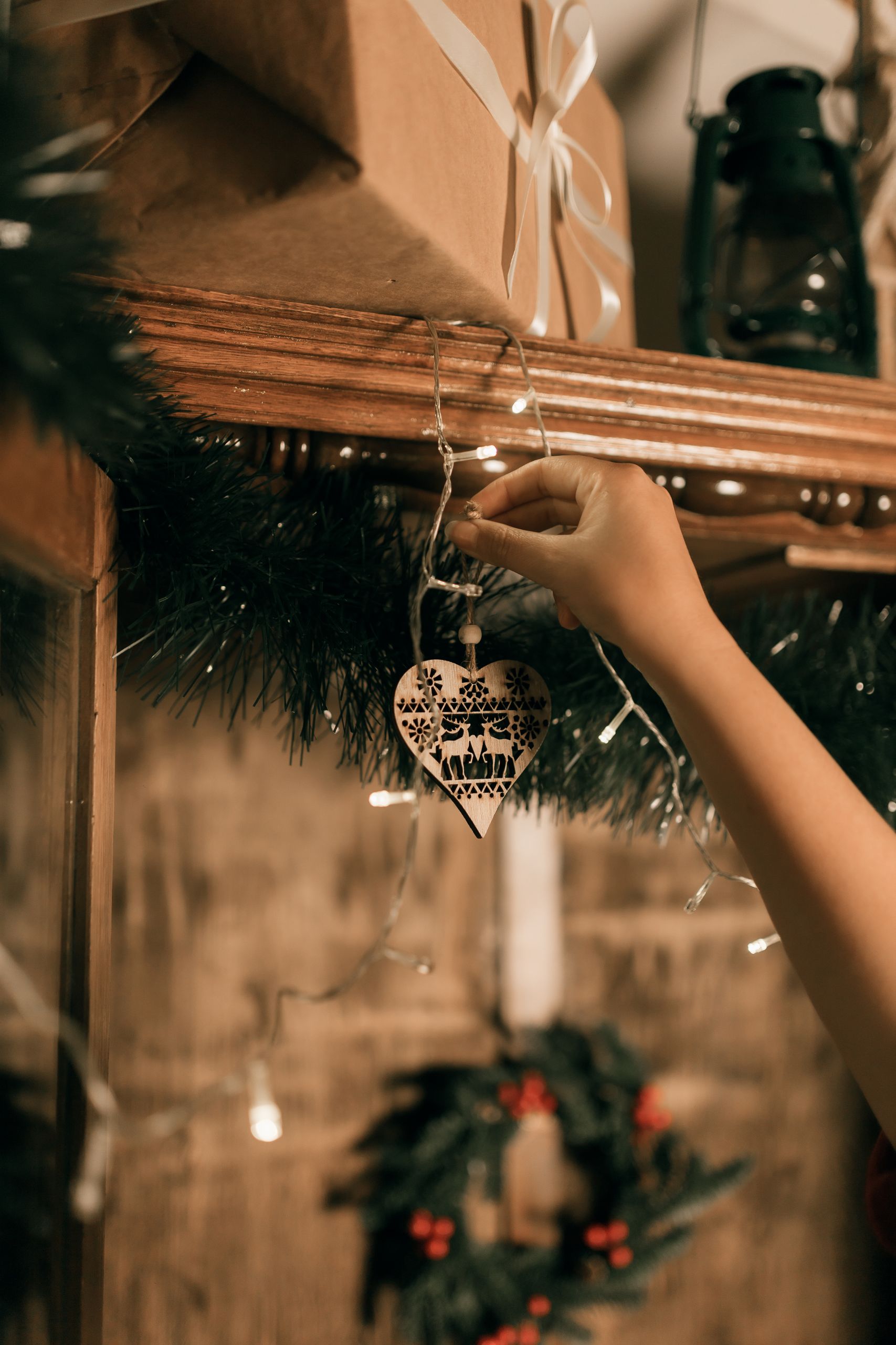 Hand adding heart ornament to festive Christmas decorations indoors.