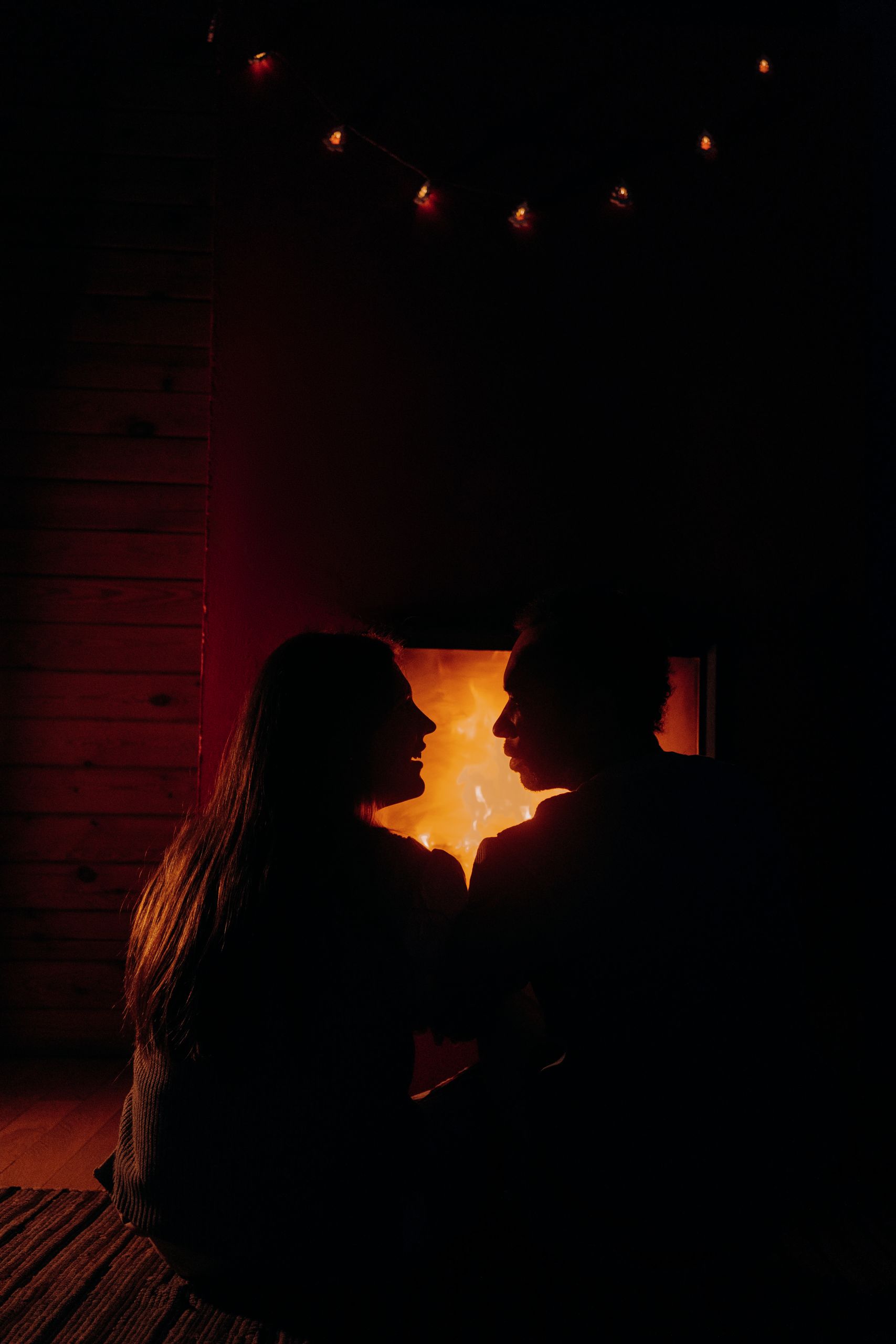 Silhouetted couple seated by a warm fireplace, evoking a Cozy Autumn Date Night Ideas at Home