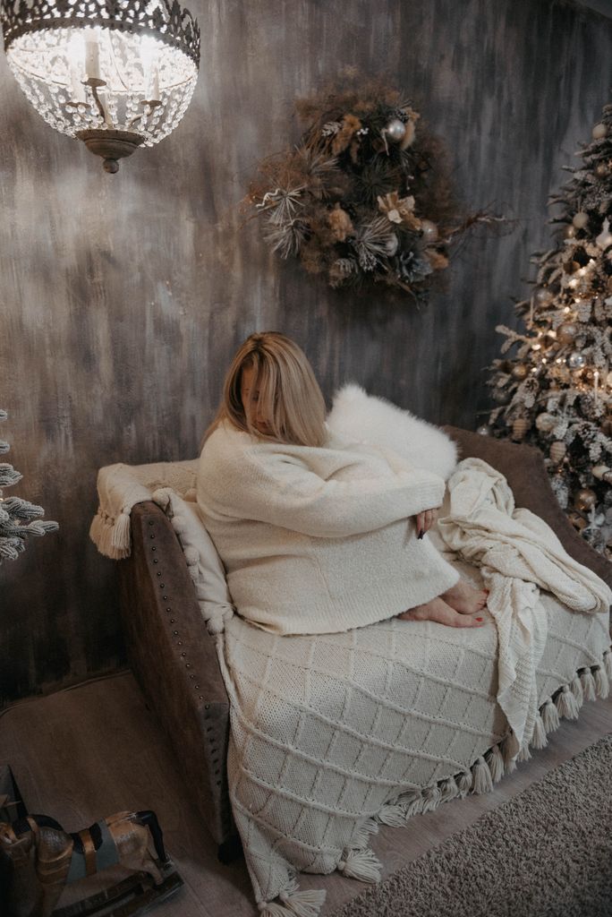 A woman relaxing on a couch with holiday decorations in a cozy room.