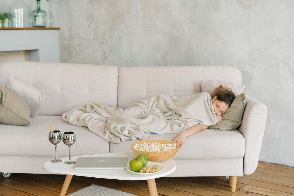 Teenage girl wearing a cozy blanket hoodie on the sofa